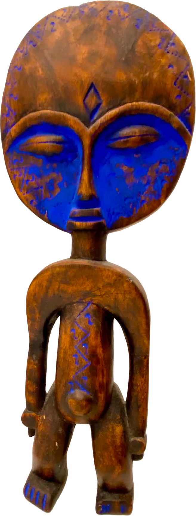 Wooden figurative sculpture with a vivid blue face on a white shelf.